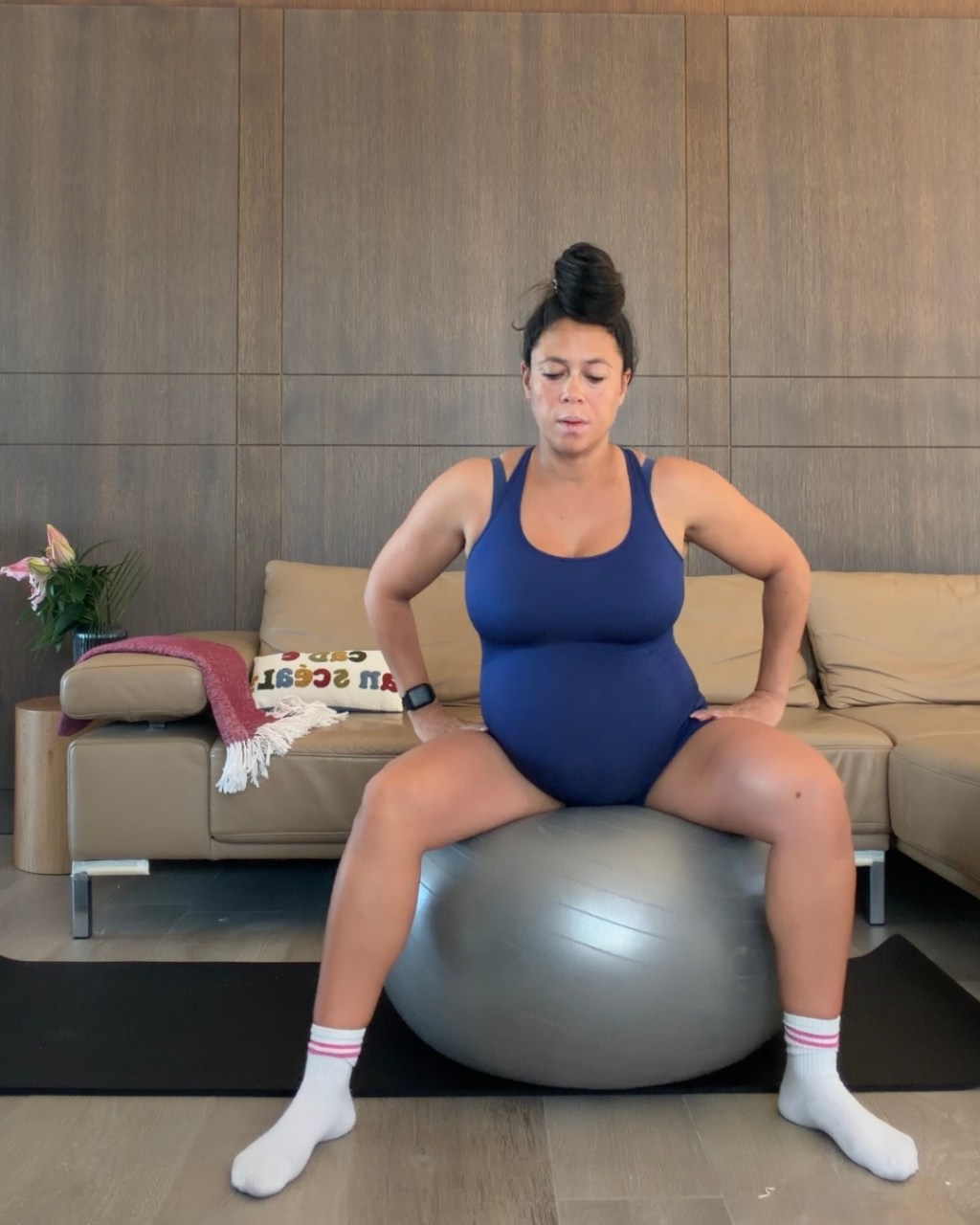 Pregnant woman sitting on a grey birth ball doing positioning exercises to turn a breech baby